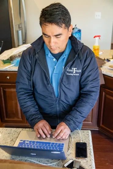 A man from Final Touch Cleaning Services  using a laptop