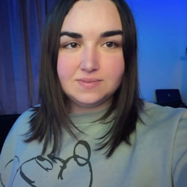 Young woman with straight dark hair wearing a light-colored sweatshirt indoors.