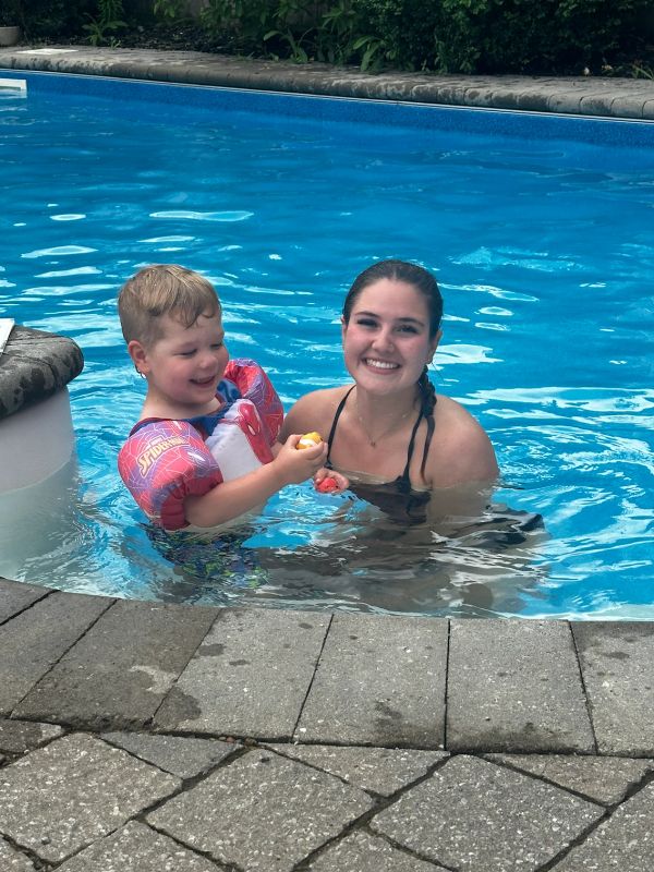 A young woman and boy happily playing in a swimming pool.