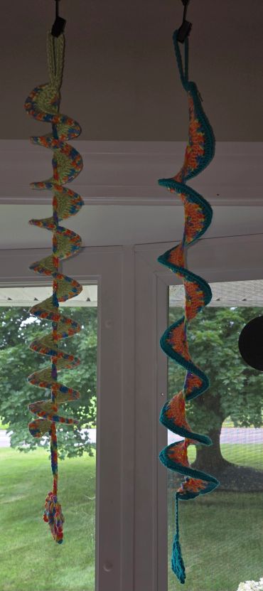 Two colorful crocheted spiral decorations hanging indoors.