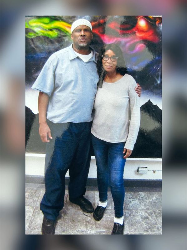 A man and woman standing together against a colorful mural.