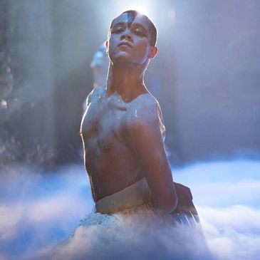Male ballet dancer in dramatic pose with theatrical makeup and fog effects.