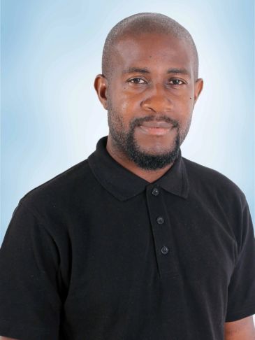 Man in a black polo shirt smiling gently.
