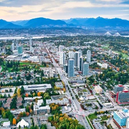 Aerial view of a city with tall buildings and mountains in the background.