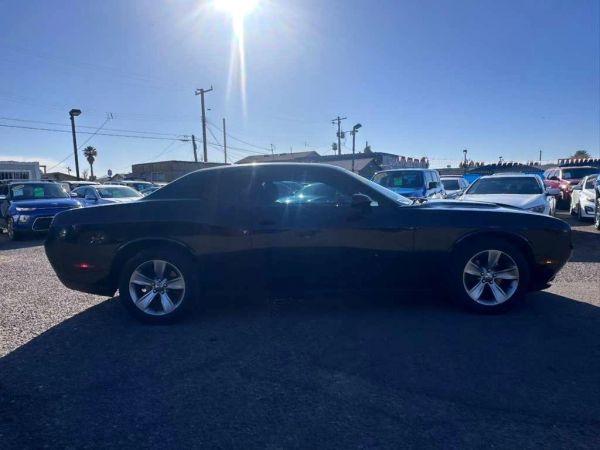 Black muscle car parked on gravel under a bright sun.
