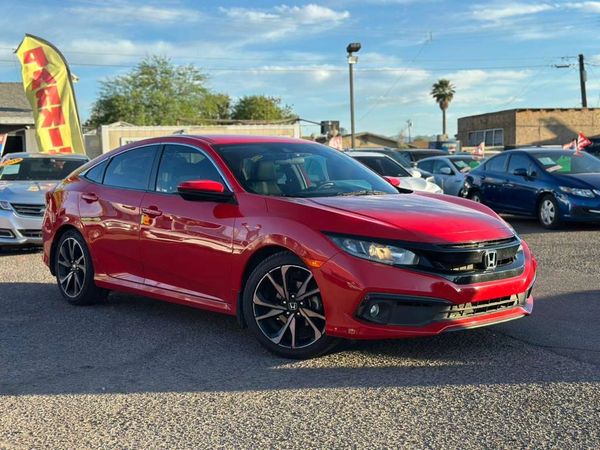 Red Honda sedan parked outdoors on a sunny day.