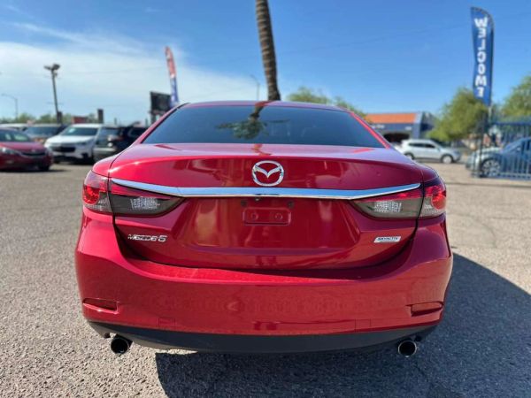 Red Mazda sedan rear view in a parking lot.