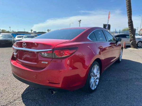 Red Mazda sedan parked outdoors on a sunny day.