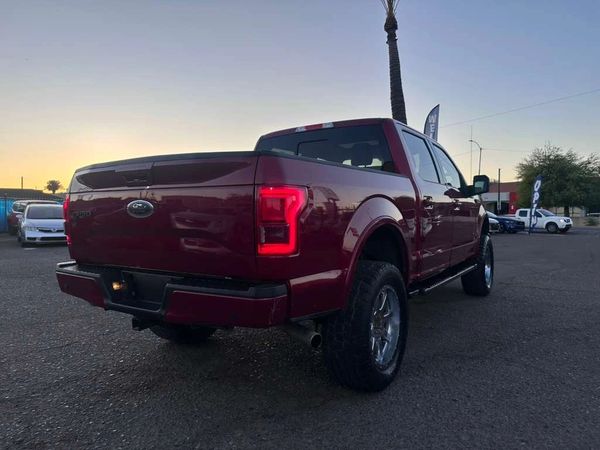 Red Ford pickup truck parked at sunset with visible taillights.