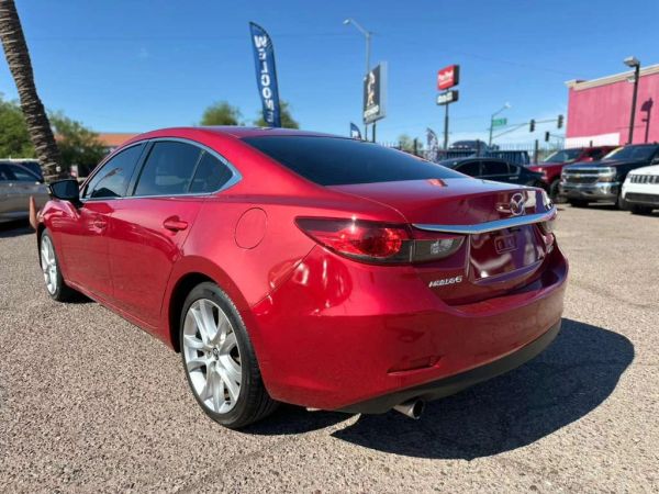 Shiny red Mazda sedan parked in a lot on a sunny day.