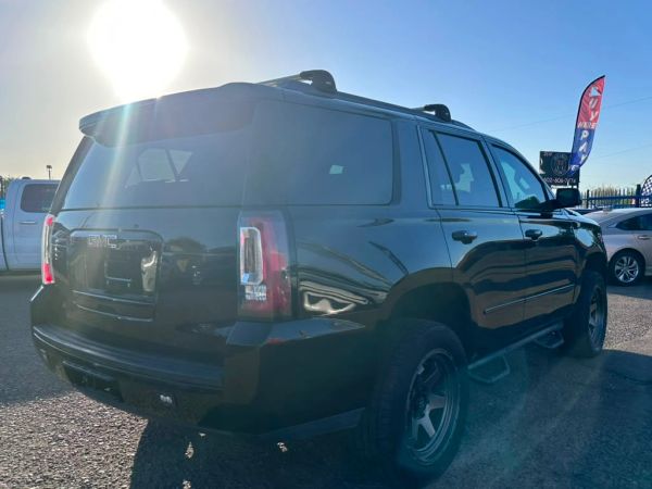 Black GMC SUV parked under bright sunlight.