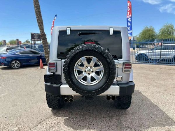 Rear view of a silver Jeep with off-road tires and dual exhausts.