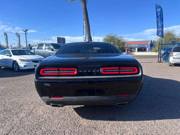 Rear view of a black Dodge Challenger under a clear blue sky.