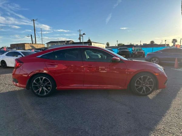 Red sedan parked in an outdoor lot at sunset.