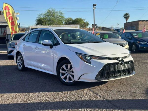 White Toyota Corolla sedan parked in a car lot under clear skies.