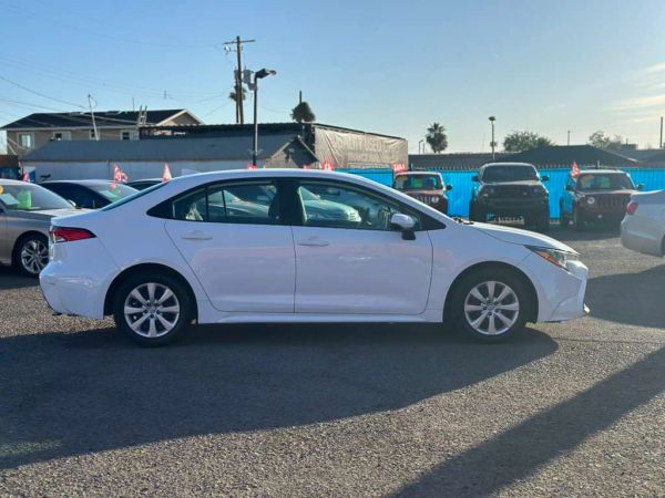 White sedan parked in a lot under clear sky.