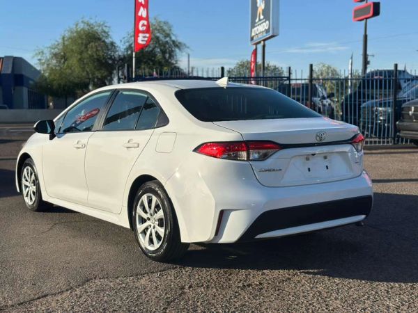 White Toyota Corolla parked in a car lot with clear skies.