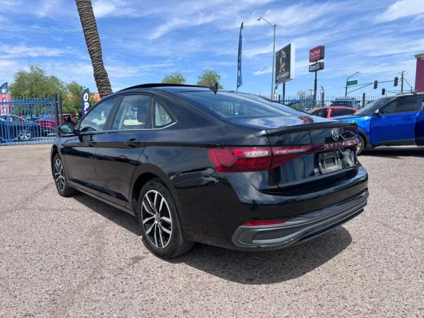 Rear side view of a black Volkswagen sedan parked outdoors.