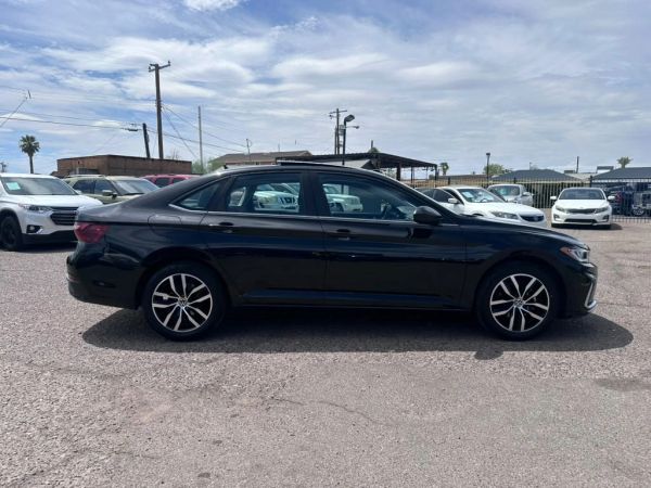 Black sedan parked outdoors on a sunny day.