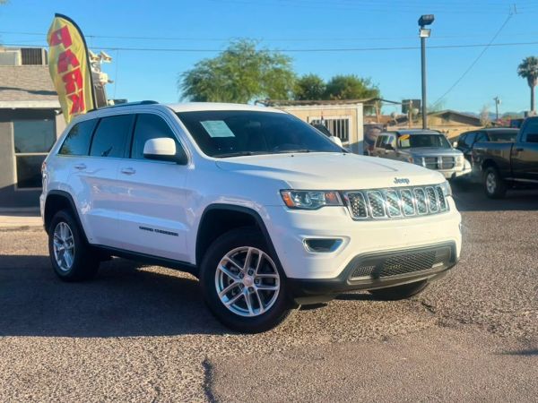 White Jeep Grand Cherokee parked in a lot.