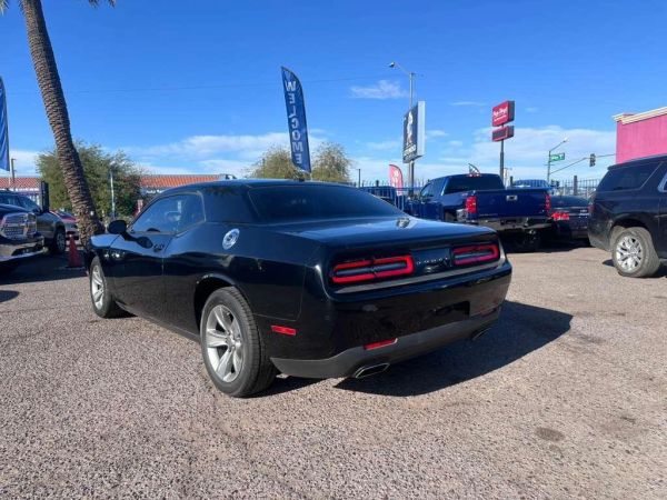 Black Dodge Challenger parked outdoors with a clear blue sky.