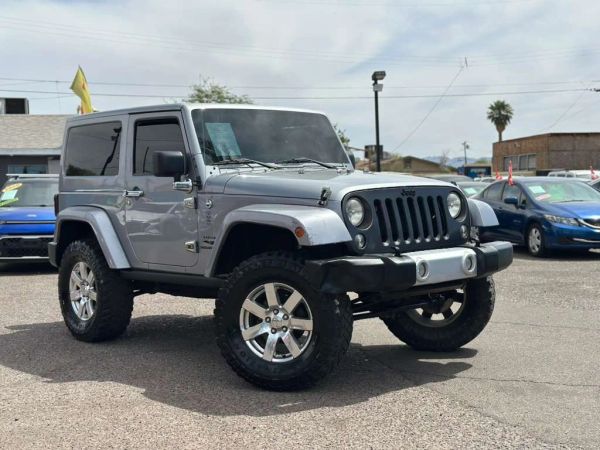 Silver Jeep Wrangler parked outside on a sunny day.