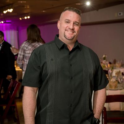 Man smiling at a formal event wearing a black shirt.