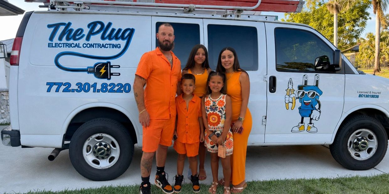 Family dressed in orange posing next to an electrical contracting van.