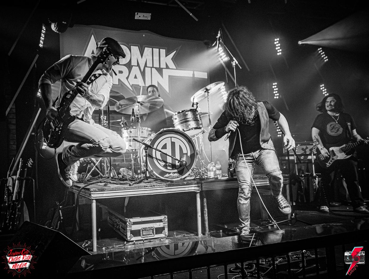 Black and white photo of a rock band performing energetically on stage.