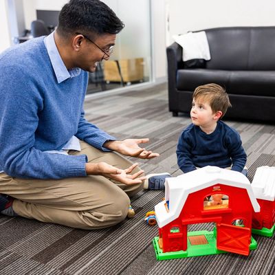 Man and child playing with a toy barn indoors.
