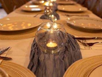 Elegant table setting with glowing candle centerpiece and woven placemats.