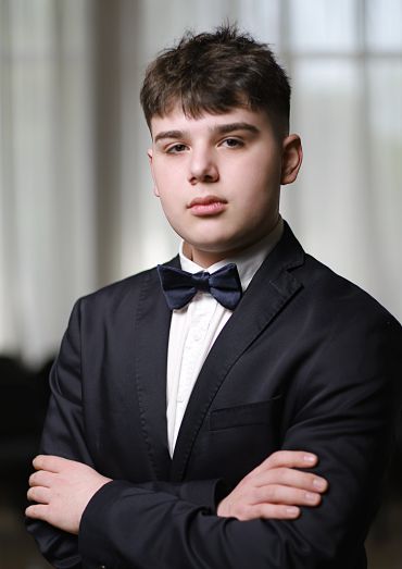 Young man in a suit with a bow tie posing confidently.