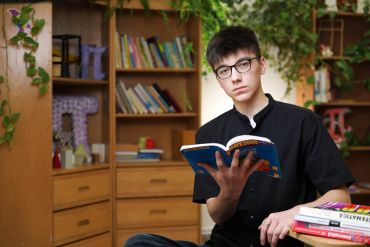 Teenage boy reading a book indoors.