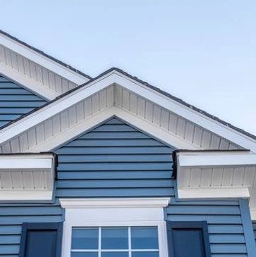 Blue house exterior with white trim and a window below the roof.
