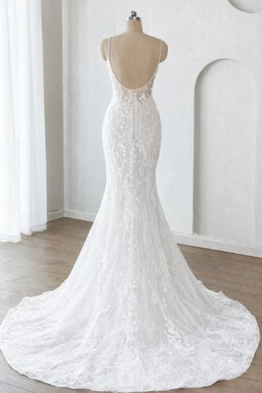 Back view of elegant white lace wedding gown with a long train on a mannequin.