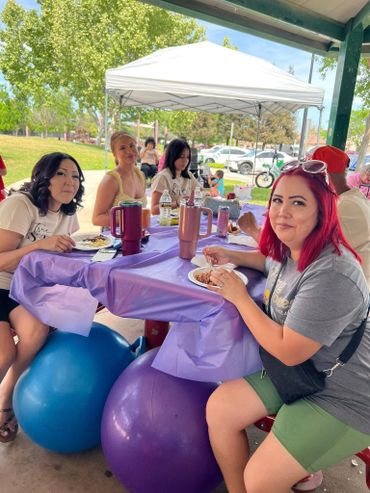 Group of women enjoying food while sitting on exercise balls at a picnic table.