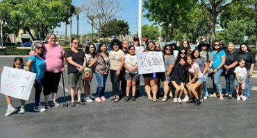 A diverse group of people holding signs in a sunny outdoor setting.