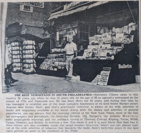 Old newspaper picture of man in front of newsstand on street corner with magazines