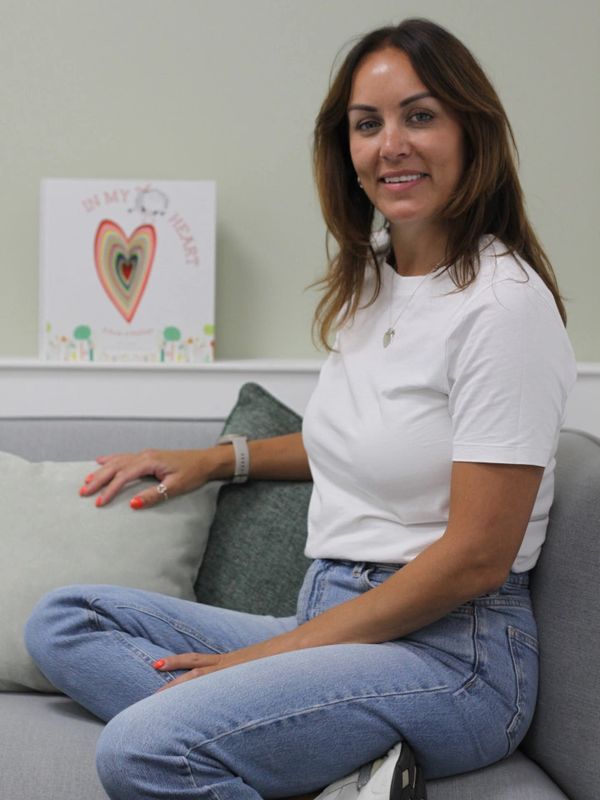 Woman sitting on a couch smiling.