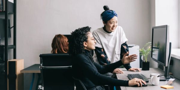 Two women collaborating at a computer in an office.