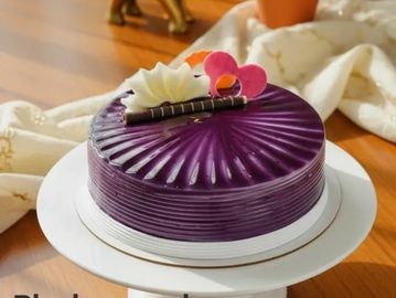 A glossy purple cake with white and pink decorations.