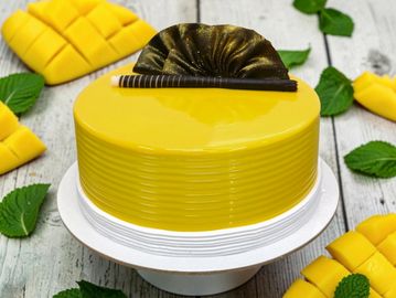 Glossy yellow mango mousse cake with chocolate decoration.