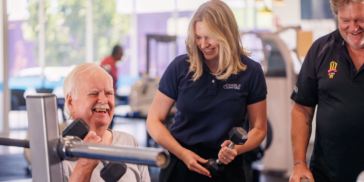 Clinician smiles with older adults in accessible gym