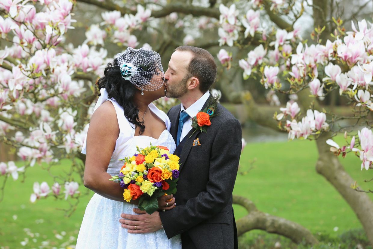 groom and bride kissing in front of cherry tree

