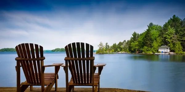 Two small wooden chairs kept together near a pond