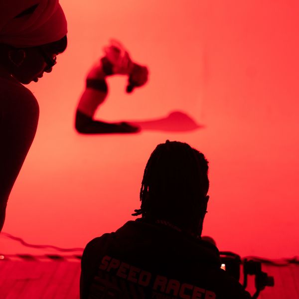 Silhouetted individuals watching a gymnast against a red background.