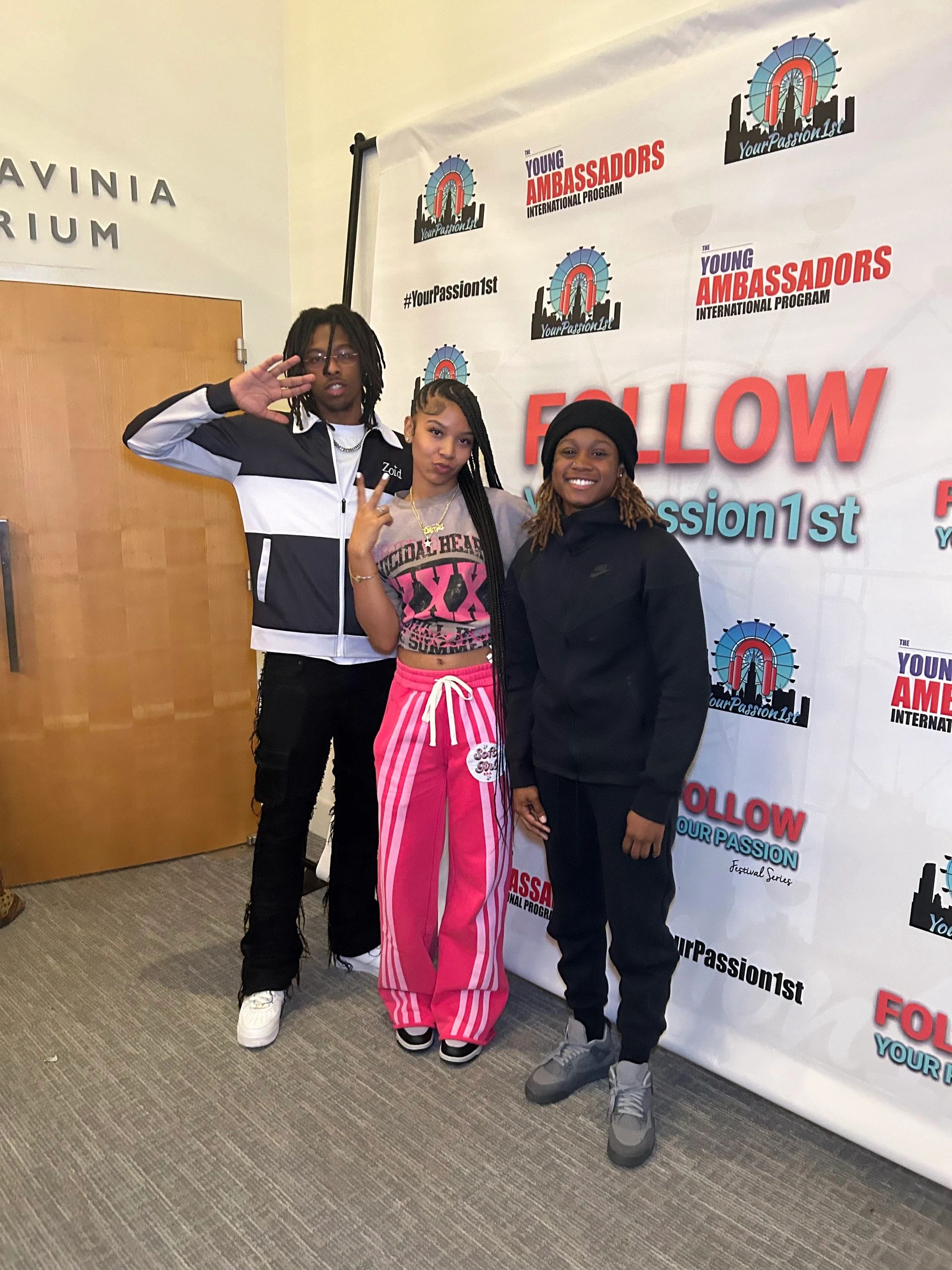 Three young people posing in front of a backdrop for a youth ambassador program.