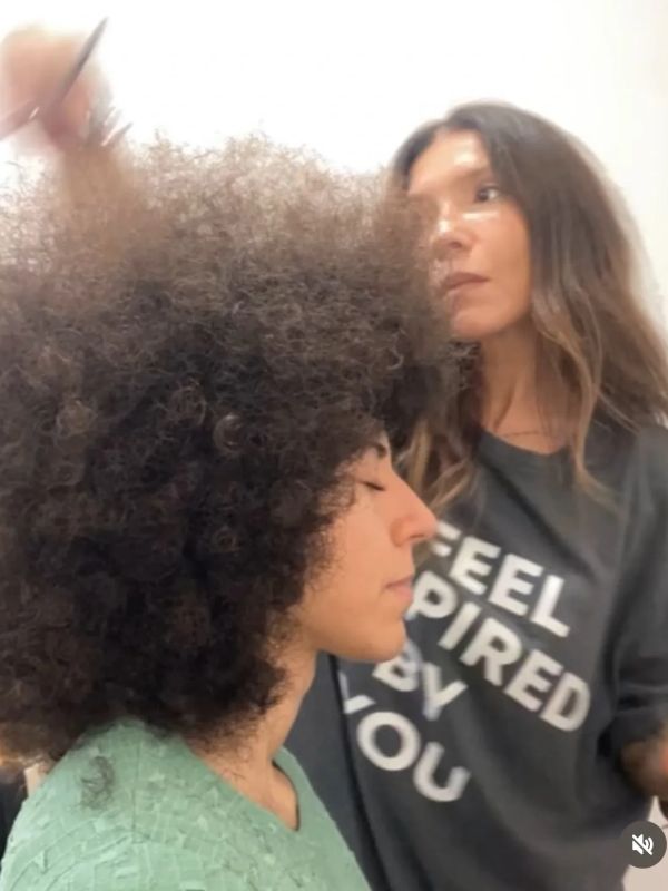 Una mujer peina a otra con cabello rizado.