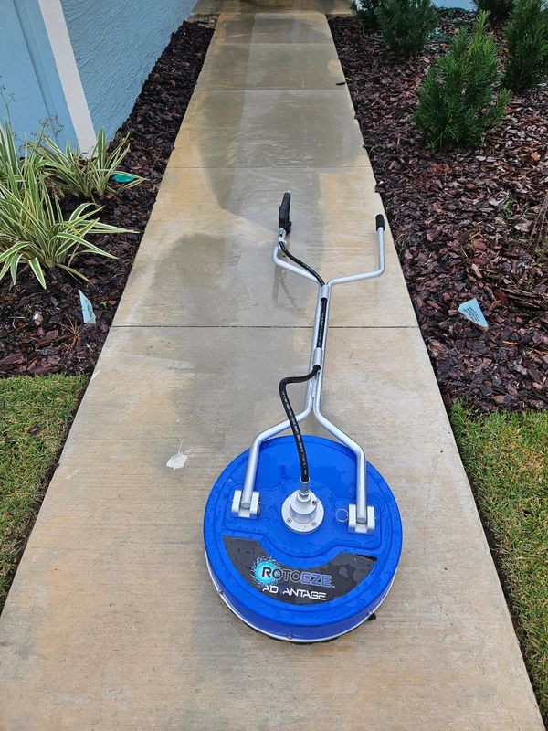 A blue surface cleaner on a wet concrete sidewalk.
