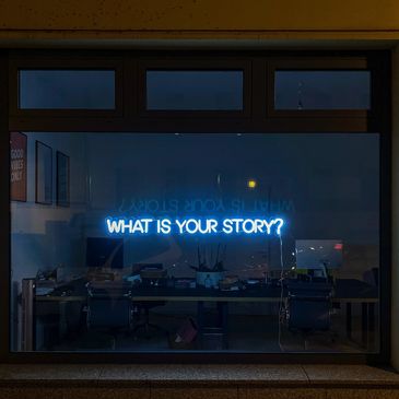 A photo of a light sign asking, "What is your story?"